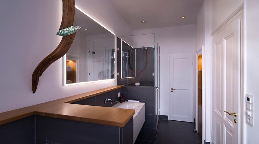 Saniertes Badezimmer mit schwarzen Fliesen und großem Spiegel