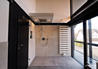 Großzügige, bodengleiche Regendusche mit moderner Duscharmatur, Glasabtrennung und Handtuchheizkörper