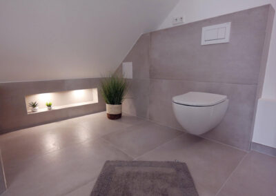 Modernes Badezimmer mit wandhängendem WC, integrierter Vorwandinstallation und beleuchteter Wandnische