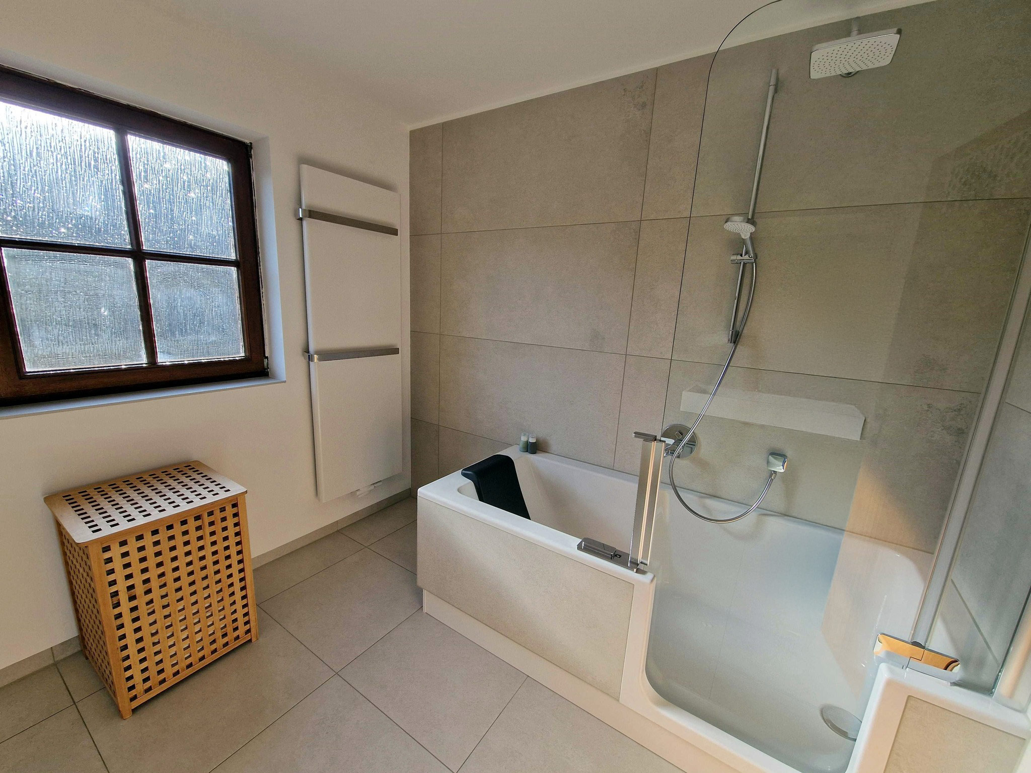 Modernes Badezimmer mit Badewanne, integrierter Duschlösung und Glasabtrennung