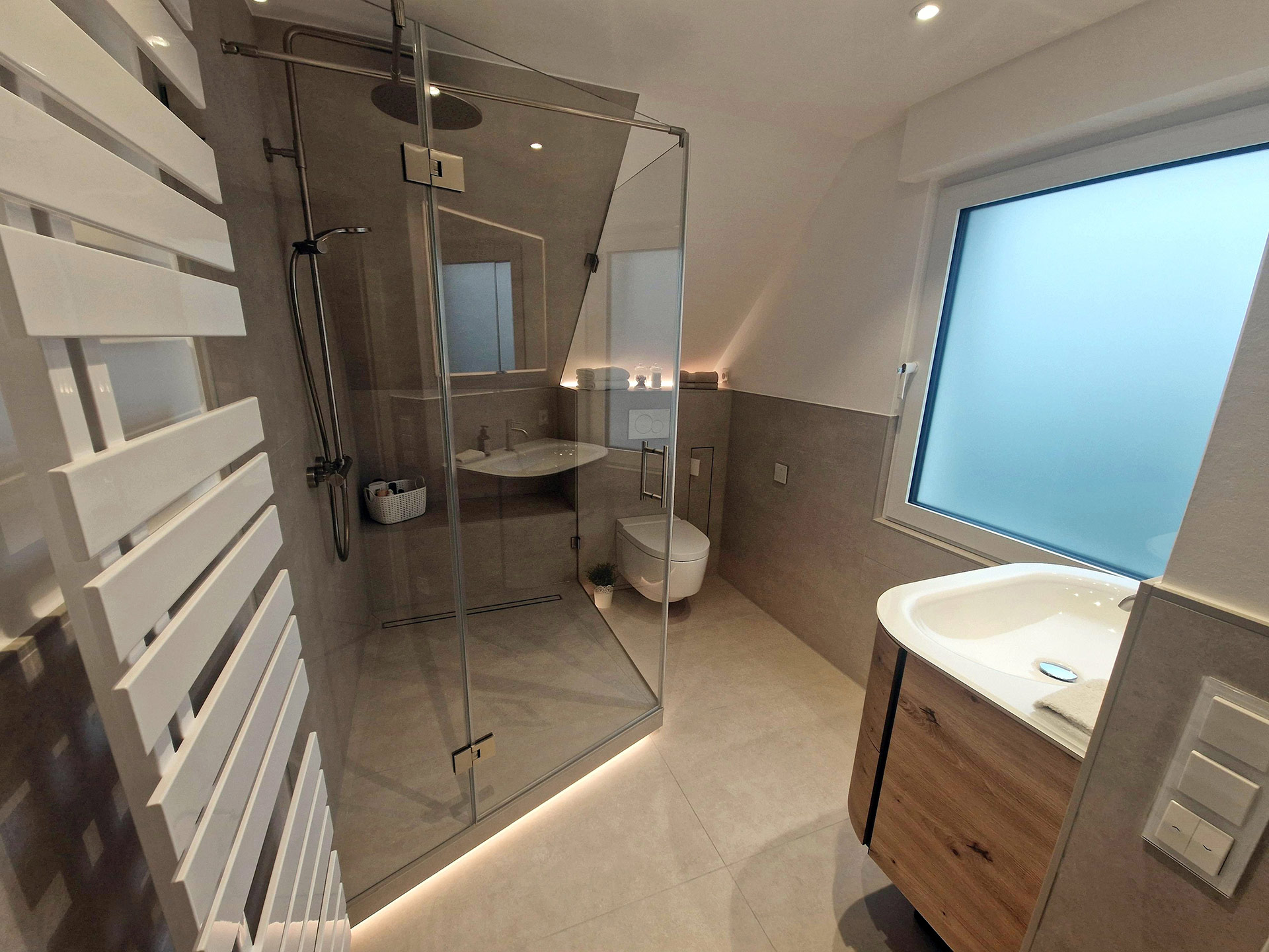 Hochwertig saniertes Badezimmer mit bodengleicher Glasdusche und Beleuchtung, Waschtisch in Holzoptik und Handtuchheizkörper
