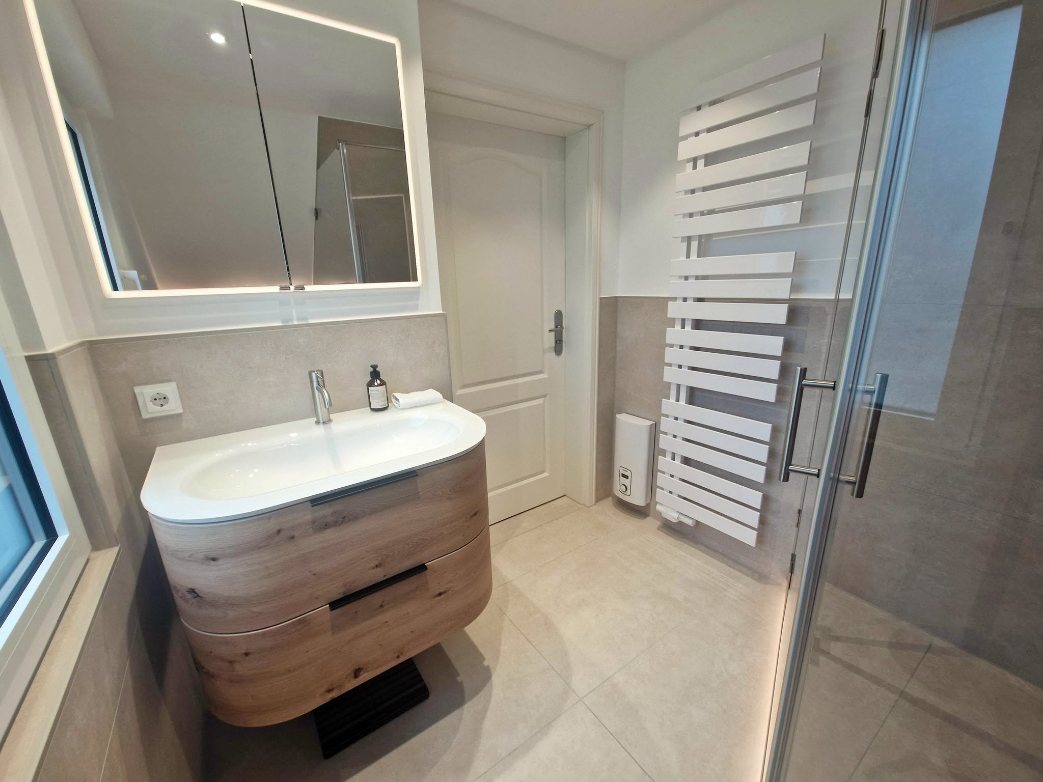 Modernes Badezimmer mit bodengleicher Dusche, wandhängendem WC und Waschtisch mit Holzoberfläche
