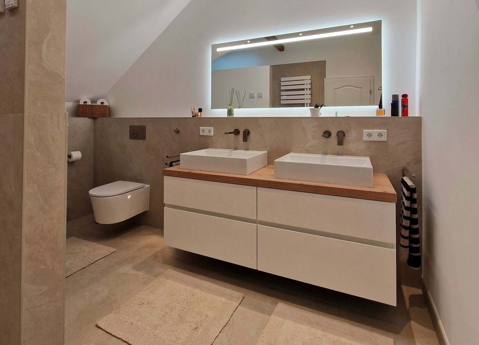 Modernes Badezimmer mit bodengleicher Dusche, wandhängendem WC und Waschtisch mit Holzoberfläche